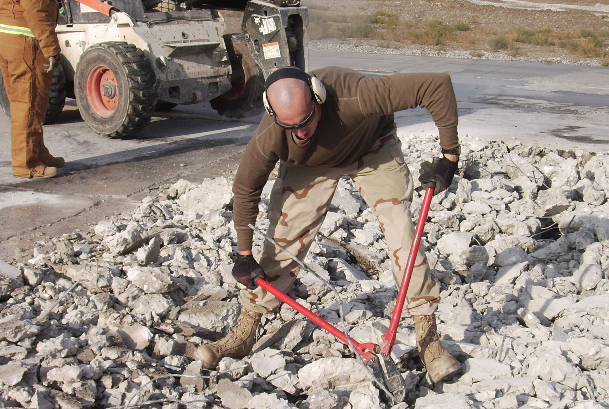 Staff Sgt. David Galbraith, 455th Expeditionary Civil Engineer Squadron craftsmen, cuts a wire that was buried in the taxiway Nov 18. The taxiway collapsed after a sinkhole formed underneath it. It took Airmen from across the wing to work together to complete the project  without interrupting the various missions on the flightline.  (U.S. Air Force courtesy photo)