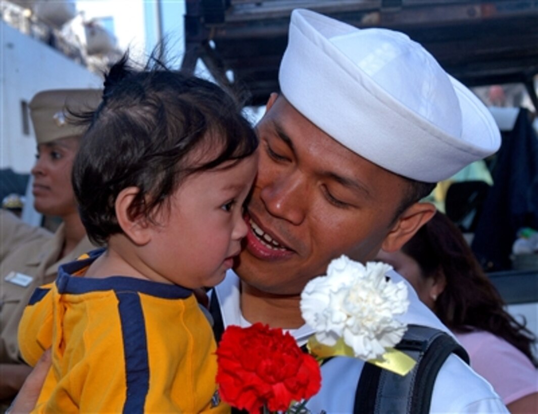 U.S. Navy Petty Officer 3rd Class Floro Cellona embraces his son at the homecoming ceremony for the Military Sealift Command hospital ship USNS Mercy in San Diego, Calif., Sept. 29, 2006.