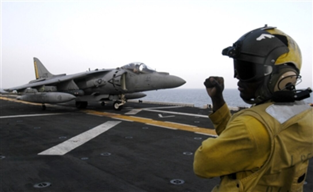 U.S. Navy Petty Officer 3rd Class Manuel A. Paulino signals the pilot of an AV-8B Harrier to hold position on the flight deck of the USS Iwo Jima (LHD 7) on Sept. 19, 2006.  The Iwo Jima began a six-month deployment to the U.S. European Command and U.S. Central Command areas of responsibility to conduct maritime security operations.  Paulino is a Navy Aviation Boatswain's Mate Handler.  