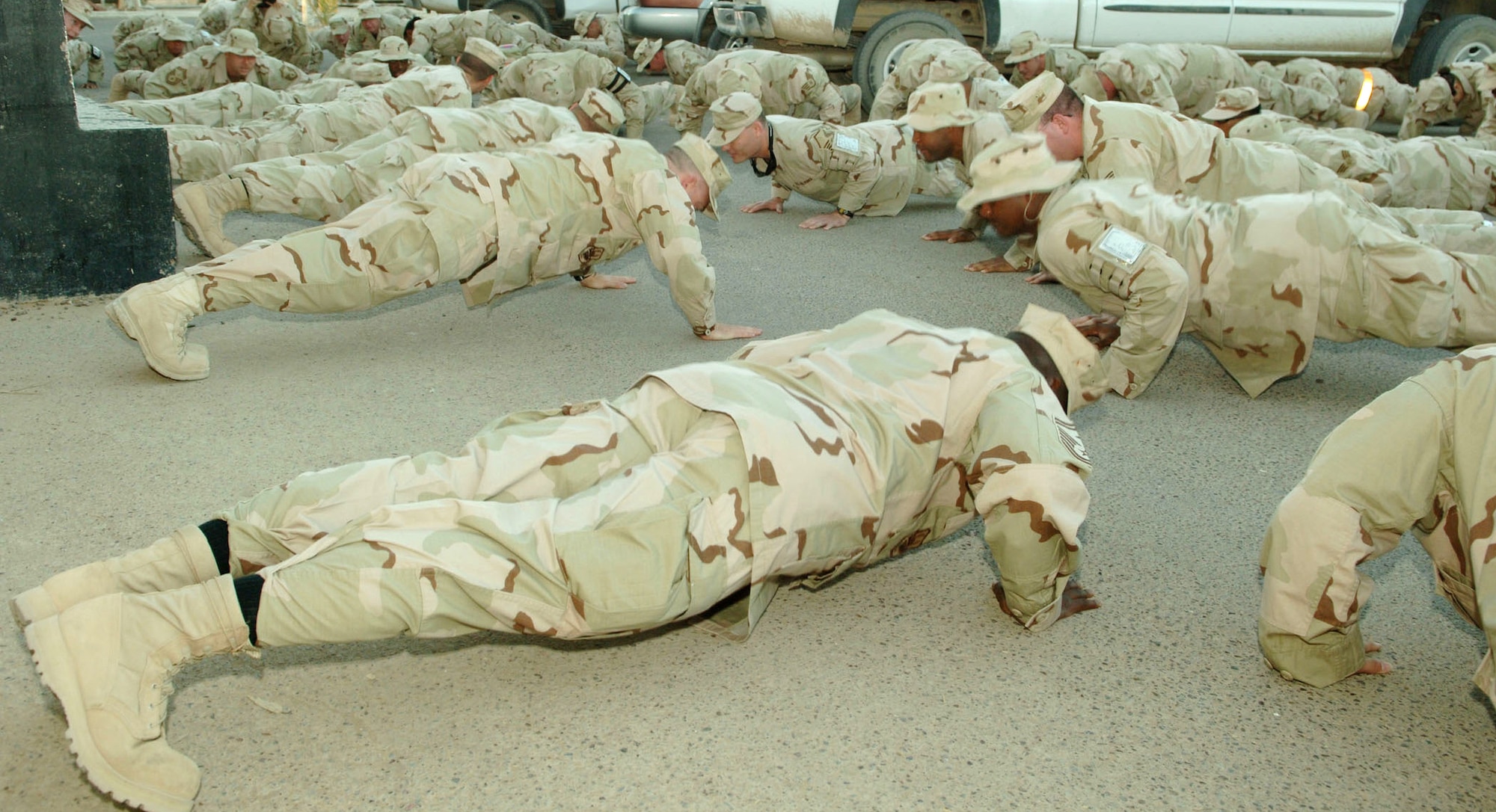 Airmen from the 332nd Expeditionary Communications Squadron at Balad Air Base, Iraq, perform push-ups in front of their building. The squadron plans to do 332,000 push-ups collectively before their deployment here ends.  Squadron Airmen call it the "332nd 332K Push-Up Challenge."  (U.S. Air Force photo/Airman 1st Class Chad Kellum)