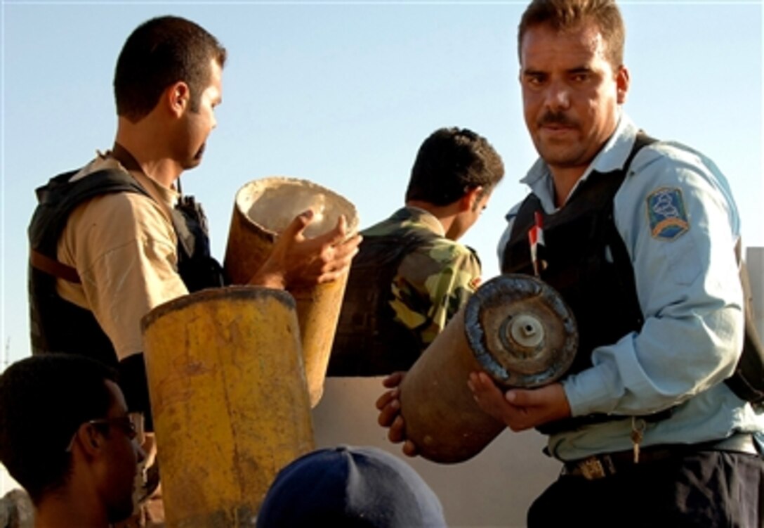 Iraqi police officers load a vehicle with weapons found during a search in Mosul, Iraq, Sept. 28, 2006. 