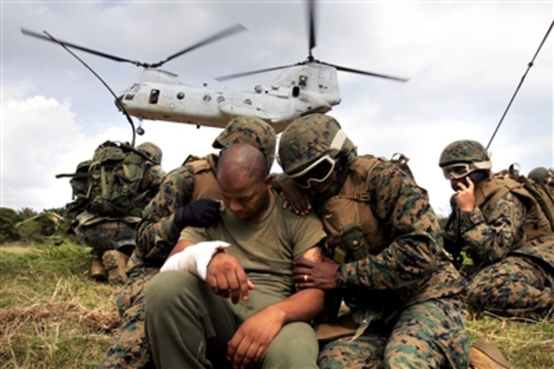 A U.S. Marine corpsman shields a simulated injured Marine from the rotor wash of a CH-46E Sea Knight helicopter during a medical evacuation exercise in Central Training Area at Camp Hansen, Okinawa, Japan, Sept. 22, 2006. During the exercise, 15 corpsmen had to treat patients.
