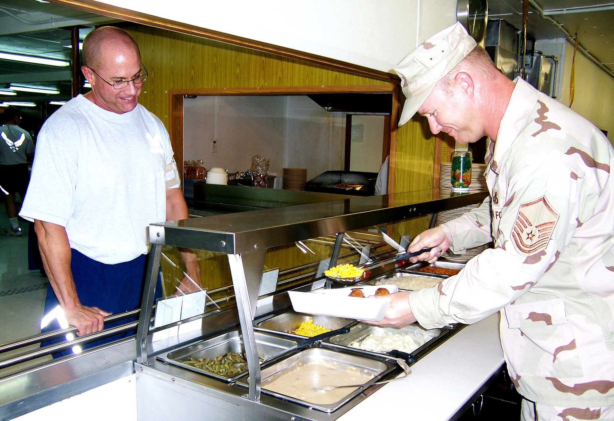 Master Sgt. Joe Ennen serves a customer Oct. 3 at the dining facility at a deployed location in Southwest Asia. Sergeant Ennen is chief of the food service flight for the 379th Air Expeditionary Wing. (U.S. Air Force photo/Tech. Sgt. Steve Staedler)