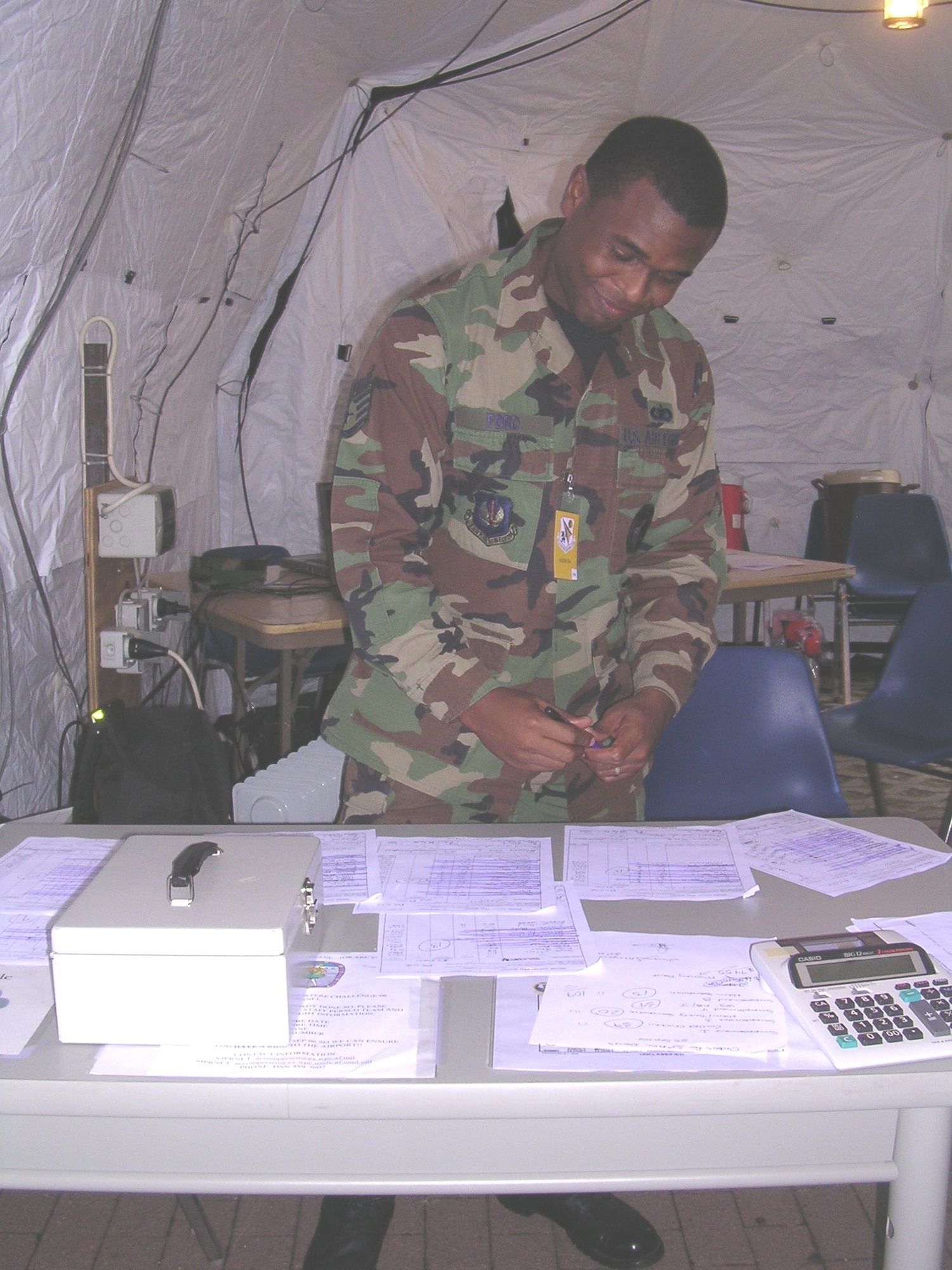 Staff Sgt. Eugene Ford, U.S. Air Forces in Europe augmentee for Exercise Austere Challenge, collects money for box lunches in the entrance tent of the 32nd Air Operations Center compound Sunday. (Photo by Capt Jennifer Lovett, USAFE/PA)