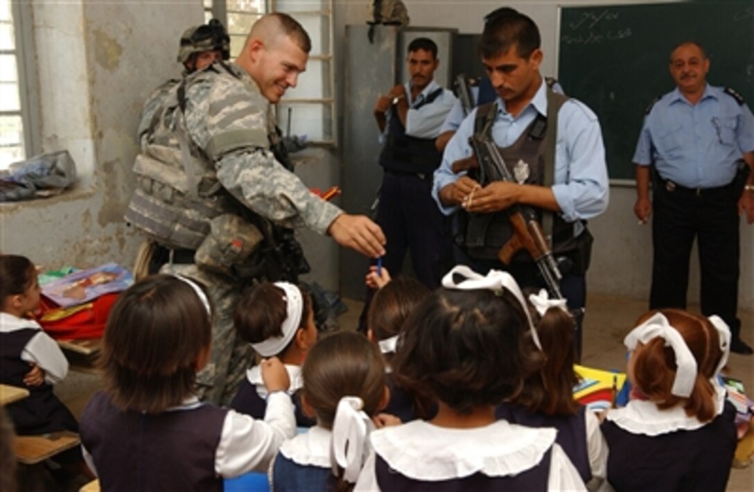 U.S. Army Staff Sgt. Shawn Smith (left) hands out school supplies to students with the help of Iraqi police officers during a visit to an elementary school in Kirkuk, Iraq, on Sept. 27, 2006.  Smith is assigned as a platoon leader with Bravo Company, 2nd Battalion, 35th Infantry Regiment, 25th Infantry Division.  