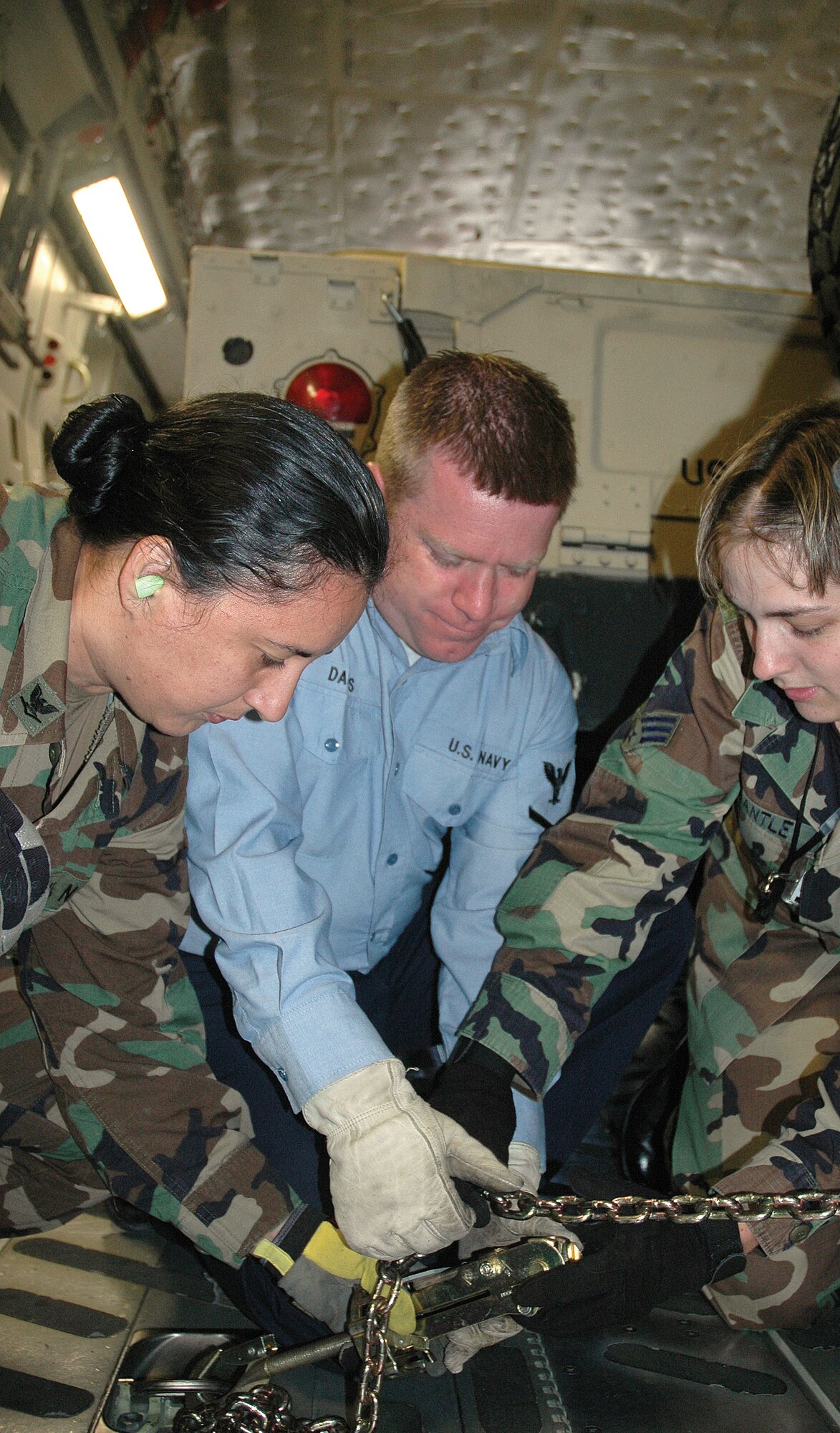 McCHORD AIR FORCE BASE, Wash., - Senior Airman Cheyenne Pantle (right) of the 86th Aerial Port Squadron, coaches Petty Officers 3rd Class Rosana Lima and Kurt Daubs in the proper use of tie downs to the floor of a C-17. This was the first time the Sailors had loaded cargo aboard a C-17. (USAF photo by Senior Airman Paul Haley)