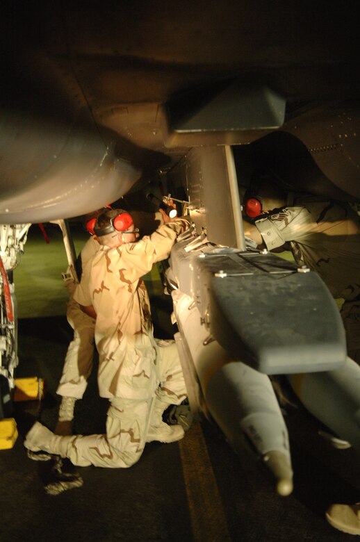 F-15E Strike Eagle weapons loaders with the 379th Expeditionary Aircraft Maintenance Squadron secure a weapons carriage containing four GBU-39/B small diameter bombs to the underside of the aircraft before it flies the first sortie carrying the new munition into combat. The Airmen are deployed from Royal Air Force Lakenheath, England. (U.S. Air Force photo/Senior Airman Ricky Best)