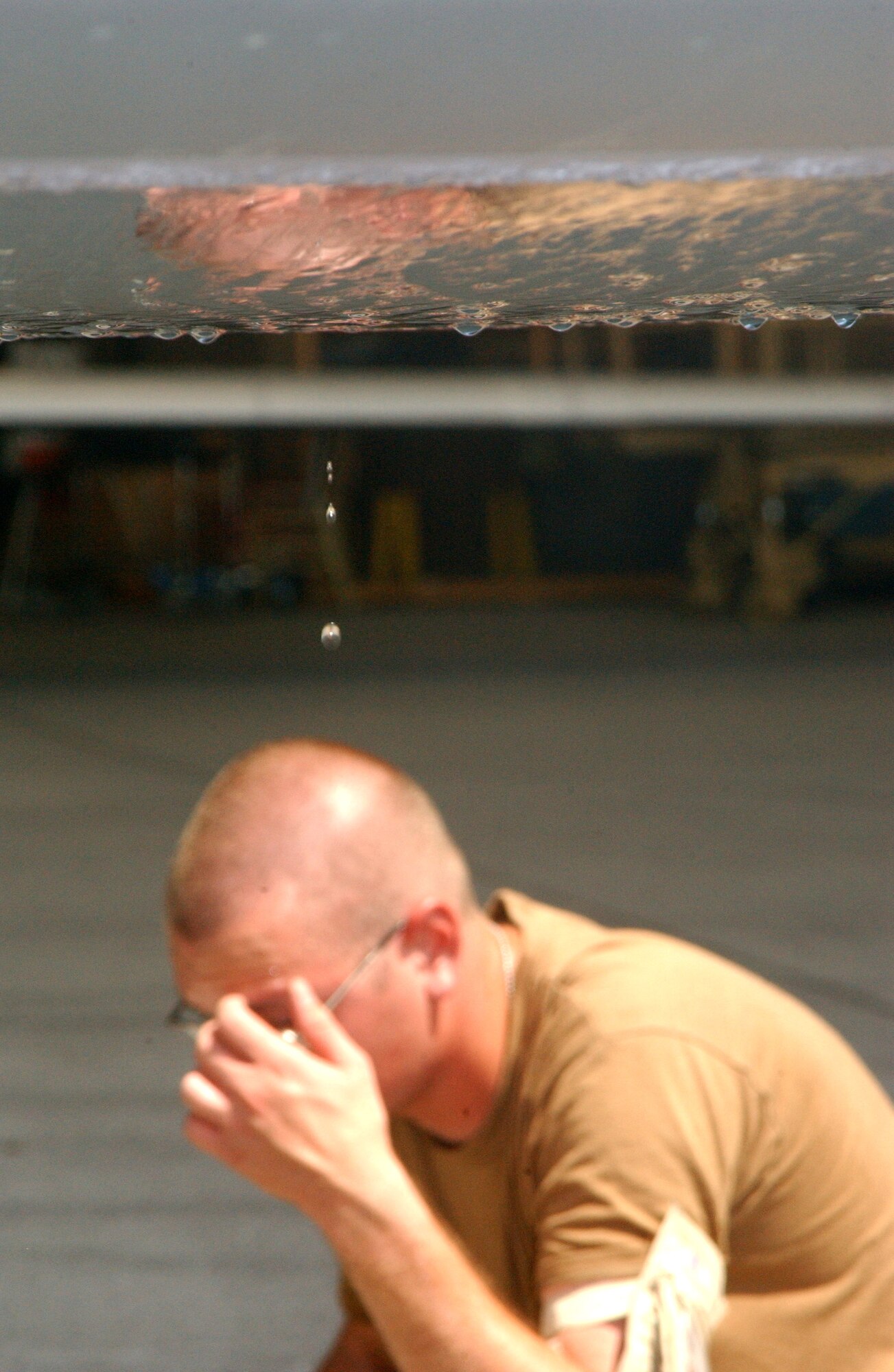 Condensation drips from the wing of a Global Hawk as Airman 1st Class Samuel Carte wipes sweat from his brow, preparing to weigh the aircraft after a mission Oct. 3 at a deployed location in Southwest Asia. The weight check is one of many post-flight checks. The Global Hawk can survey large geographic areas with pinpoint accuracy to give military decision-makers the most current information about enemy location, resources and members. (U.S. Air Force photo/Master Sgt. Jason Tudor)