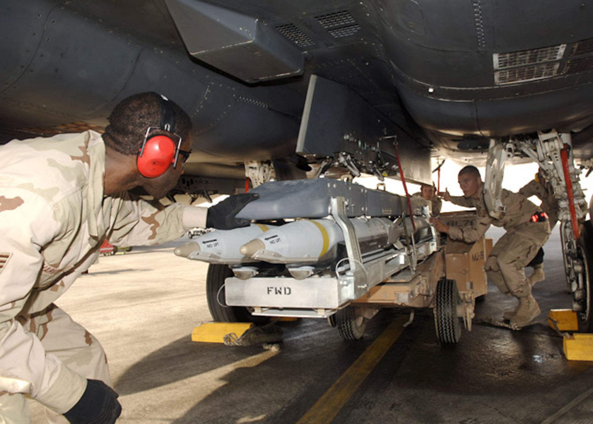 Staff Sgts. Kevin Harvey and Chace Morris and Airman 1st Class Amanda Hicks, weapons load team members from the 379th Expeditionary Aircraft Maintenance Squadron upload a weapons carriage with GBU-39/B small diameter bombs to the underside of an F-15E Strike Eagle. The jet flew its first sortie carrying the new munition into combat Oct. 5. The Airmen are deployed from Royal Air Force Lakenheath, England. (U.S. Air Force photo/Senior Airman Ricky Best) 