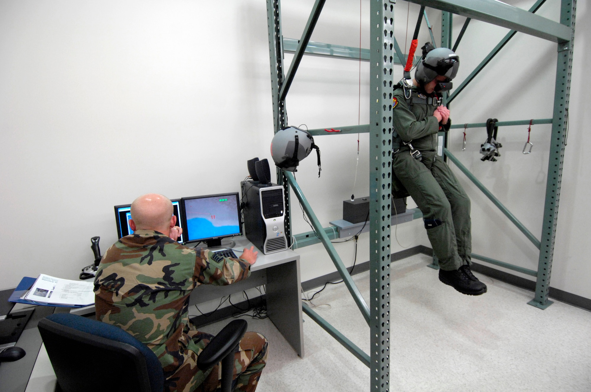 Staff Sgt. Matt Magnussen starts a virtual parachute training simulation while 1st Lt. John Brantuk II gets into his freefall position at Hickam Air Force Base, Hawaii, on Oct. 4. Sergeant Magnussen is a life support instructor with the 15th Operations Support Squadron. Lieutenant Brantuk is a pilot with the 535th Airlift Squadron (U.S. Air Force photo/Tech. Sgt. Shane A. Cuomo)
