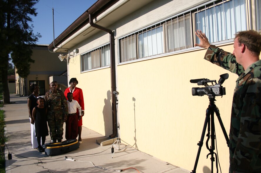 Airman 1st Class Alex Griffin, AFN Det. 7 broadcaster, films  Tech. Sgt. Kevin Ward and his family for a holiday greeting message Tuesday. (U.S. Air Force photo by Staff Sgt. Oshawn Jefferson)