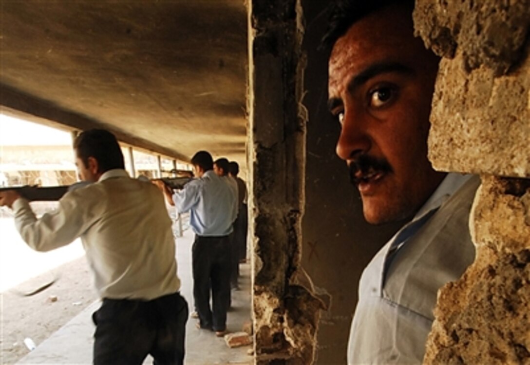 An Iraqi police recruit team leader watches as Iraqi Police recruits guard the perimeter during close-quarters combat training at the Phoenix Academy in Ramadi, Iraq, Sept. 25, 2006.