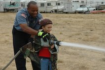 Alex Dreyer-Schumert, son of Maj. Kristi Dreyer, gets an education on fire safety during the Kids Understanding Deployment event held at Travis Air Force Base, Calif.,  Oct. 4. KUDOS is designed to give Travis children a chance to experience a deployment. (U.S. Air Force Jennifer Brugman/60th AMW Public Affairs)