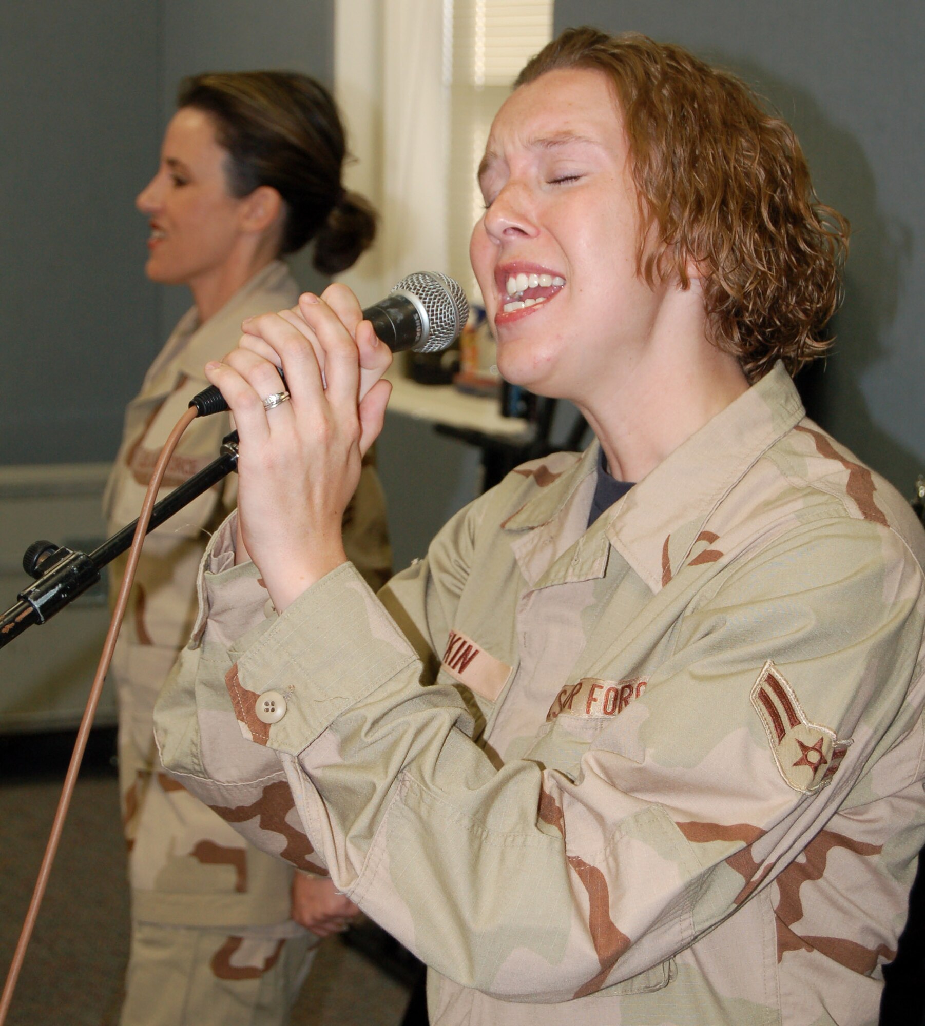 Airman 1st Class Melissa Plotkin (front) sings with fellow vocalist Tech. Sgt. Donna Siler during a rehearsal Oct. 4.   Both are with the Air Force Band of the West's Top Flight rock band at Lackland Air Force Base, Texas.  The band will be deploying soon to Southwest Asia.  (U.S. Air Force photo/Staff Sgt. Shad Eidson) 