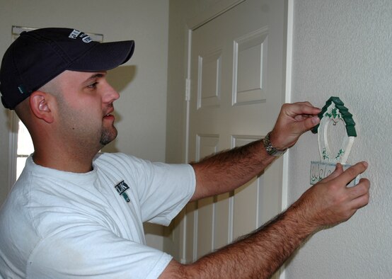 BUCKLEY AIR FORCE BASE, Colo. -- Staff Sgt. Josh Gordon, 460th Comptroller Squadron, hangs his welcome home key holder on the wall next to the front door in his new home at Buckley Air Force Base. Sergeant Gordon and his family are one of 14 families moving into family housing this week.  Phase one, which opened 28 units this week, has families moving through the end of October. Phase two has 32 units scheduled to open in November. Homes will be opening up in phases through April, with a total of 351 to be available. (U.S. Air Force photo by Staff Sgt. Sanjay Allen)