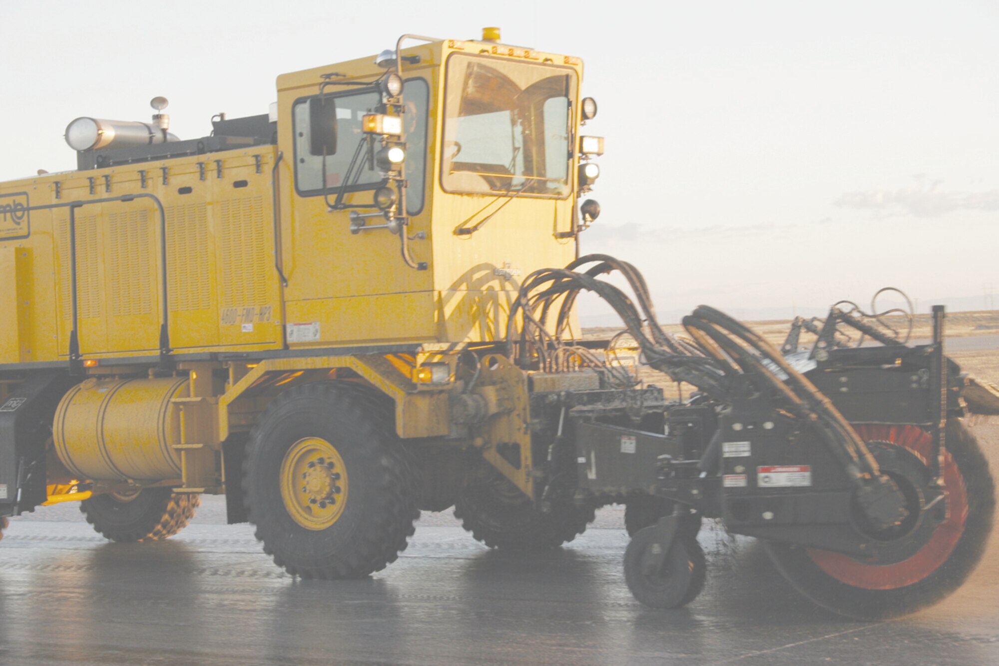 Members of the 366th Civil Engineer Squadron paving and equipment flight, remove rubber deposits on the flightline. When the jets land, the tires leave marks and over time the rubber clogs the pores of the pavement causing a loss in traction upon landing. Removal takes about four hours and includes wetting the pavement, spraying a chemical and then driving trucks with spinning brushes up and down the area to scrub the pavement clean. (Photo by Staff Sgt, Jasmine Reif)
