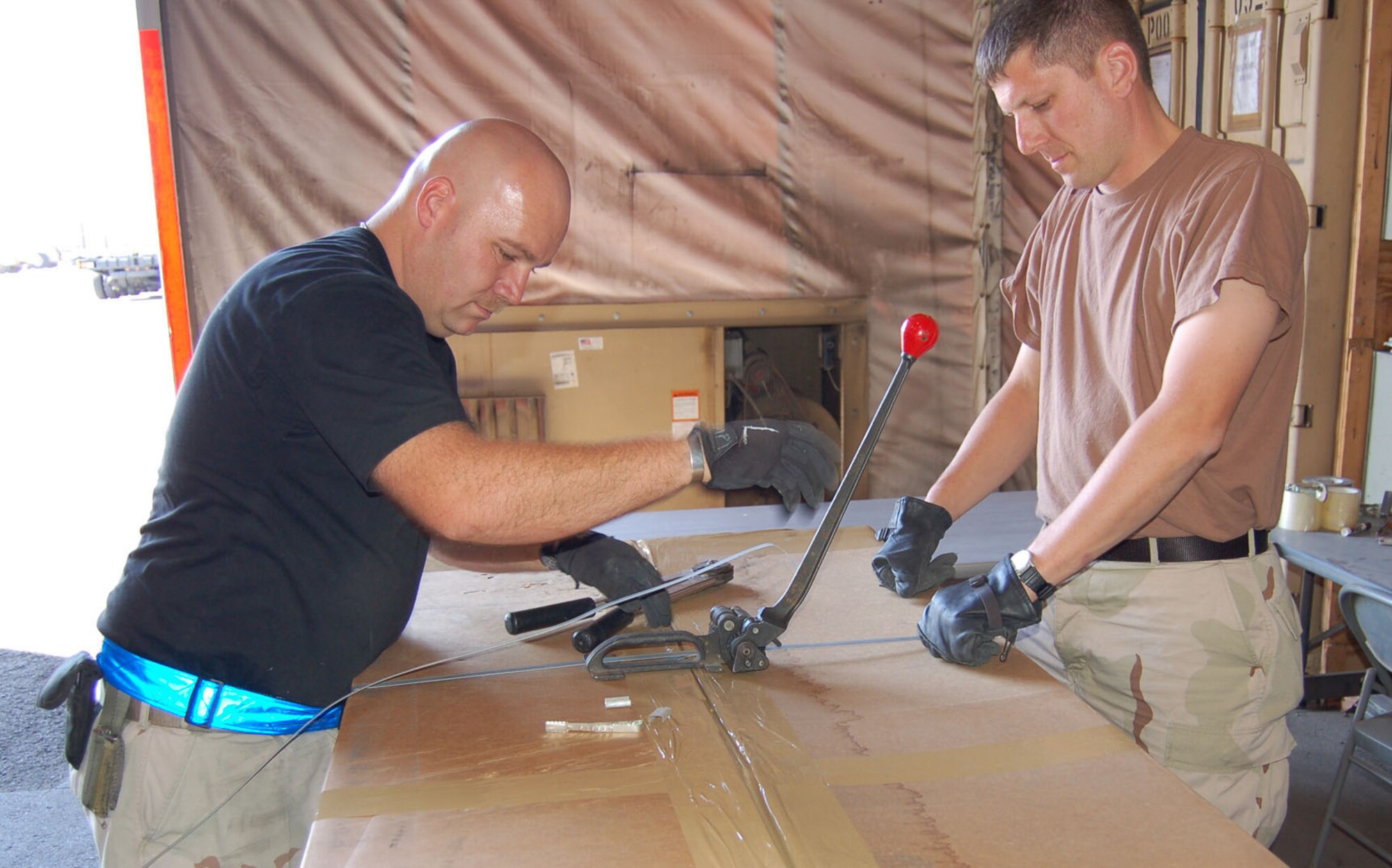 Master Sgt. Owen Meier and Tech Sgt. Jeff Helms, 376th ELRS Terminal Services secure a box of registered mail with metal bands and attached by postal seals. Both Airmen are deployed from the 911th Airlift Wing, Pittsburgh, Pa. (U.S. Air Force photo/Master Sgt. Mitch Gettle)