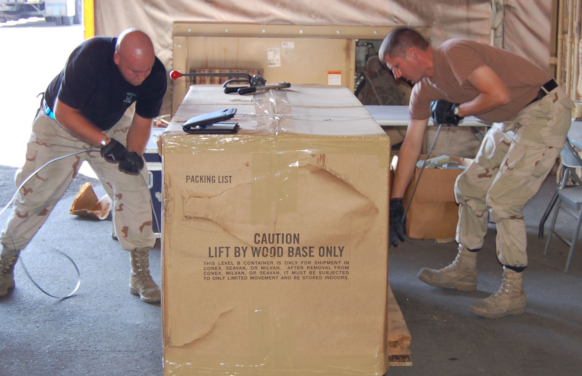 Master Sgt. Owen Meier and Tech Sgt. Jeff Helms, 376th ELRS Terminal Services secure a box of registered mail with metal bands and attached by postal seals. Both Airmen are deployed from the 911th Airlift Wing, Pittsburgh, Pa. (U.S. Air Force photo/Master Sgt. Mitch Gettle)