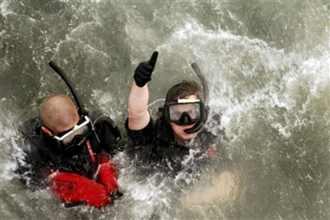 U.S. Navy Petty Officer 2nd Class Steven Ashdown and Petty Officer 2nd Class Gregory Abbott signal they are ready to be hoisted out of the water by an SH-60F Seahawk assigned to Helicopter Antisubmarine Squadron 14 during search and rescue training in Yokosuka, Japan, Oct. 3, 2006.  