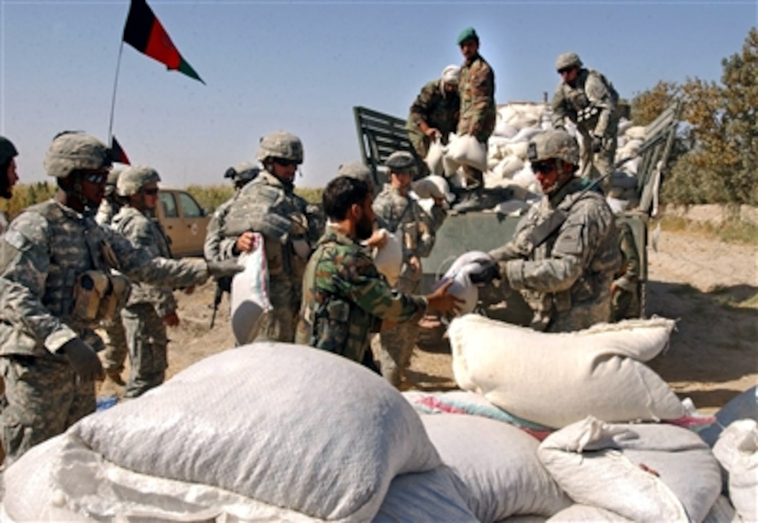 Afghan National Army and U.S. Army soldiers from Logistical Task Force 297 unload a delivery of humanitarian aid materials to be given to displaced villagers from Pashmul, Afghanistan, Oct. 4, 2006.