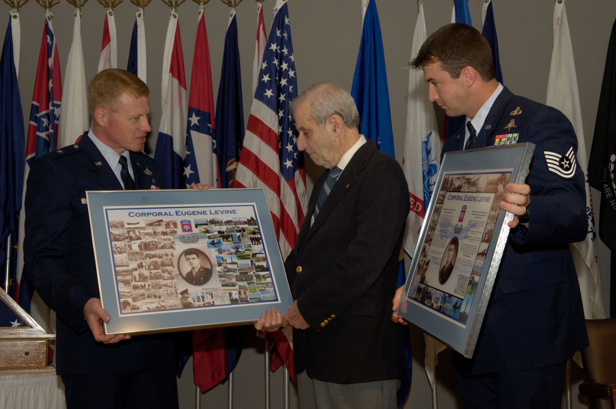 Brig. Gen. Lawrence Stutzriem and Tech. Sgt. John Lee present Dr. Eugene Levine with two collages that highlight his accomplishments as a weather forecaster during D-Day at an Oct. 6 ceremony at Arlington, Va. General Stutzriem is the director of weather and deputy chief of staff for air, space and information operations. (U.S. Air Force photo/Tech. Sgt. Cohen A. Young)