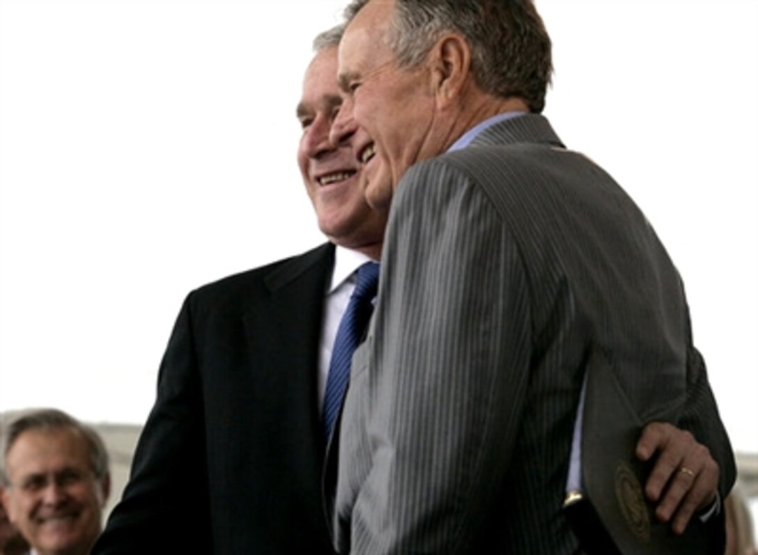 President George W. Bush hugs his father, Former President George H. W. Bush, after the christening ceremony for the newest aircraft carrier George H.W. Bush, Oct. 7, 2006. 