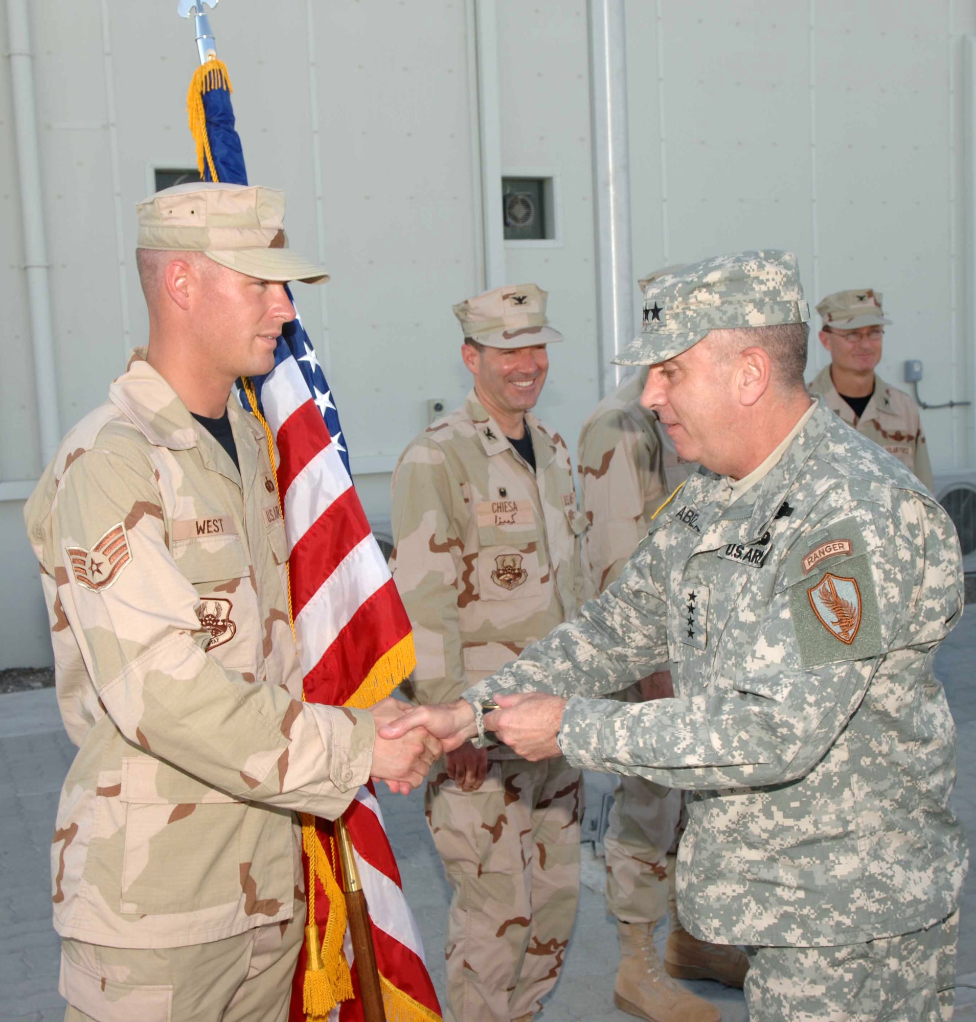 Staff Sgt. Ronald West shakes hands and accepts a coin from Army Gen. John Abizaid, commander of U.S. Central Command, Oct. 10 in Southwest Asia. General Abizaid visited this forward operating location to meet with Airmen and host-nation officials. Sergeant West is deployed to the 380th Air Expeditionary Wing. (U.S. Air Force photo/Tech. Sgt. Scott Seyer)