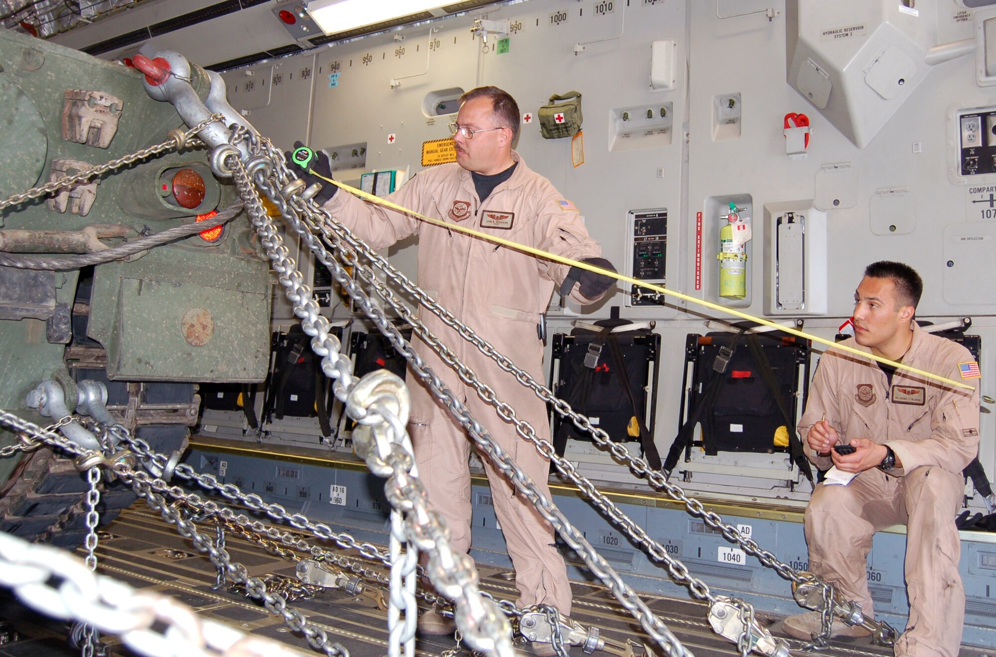 Tech. Sgt. John Woodard (left) and Senior Airman Jeramia Valentine calculate the chain strength needed to ensure the Canadian Leopard tank will not move during a flight. Both Airmen are deployed to Manas Air Base, Kyrgyzstan, from the 10th Airlift Squadron at McChord Air Force Base, Wash. (U.S. Air Force photo/Master Sgt. Mitch Gettle)