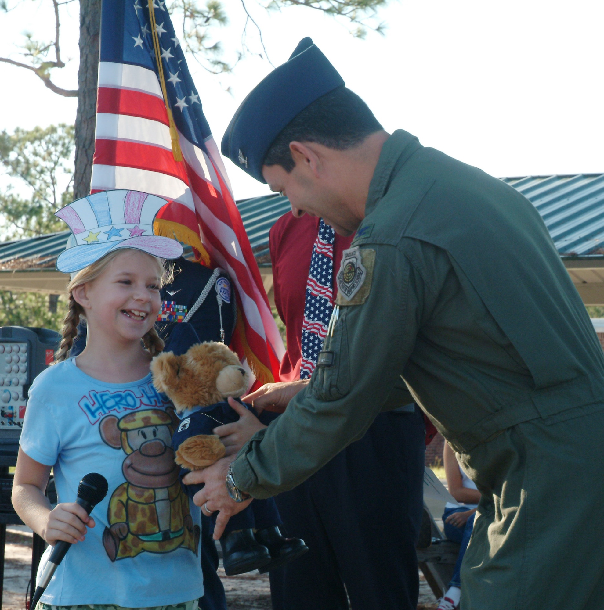 Fifth-grader Bailey Reese hands Col. Ken Wilsbach, 53d Wing commander, a bear she named “Super Hero” during the “Celebrate Freedom” ceremony Sept. 29 at Longwood Elementary in Shalimar Fla.  The bear will travel with wing members when they deploy.
