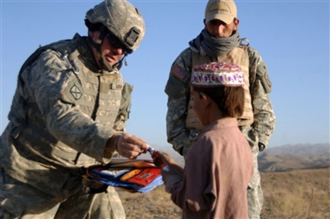 U.S. Army 1st Lt. Dan Gordon (left) hands an Afghan boy school supplies in Gomal, Afghanistan, on Oct. 4, 2006.  The supplies were donated by a school in North Dakota.  Gordon is assigned to Headquarters Platoon, Bravo Company, 2nd Battalion, 87th Infantry Regiment, 10th Mountain Division.  