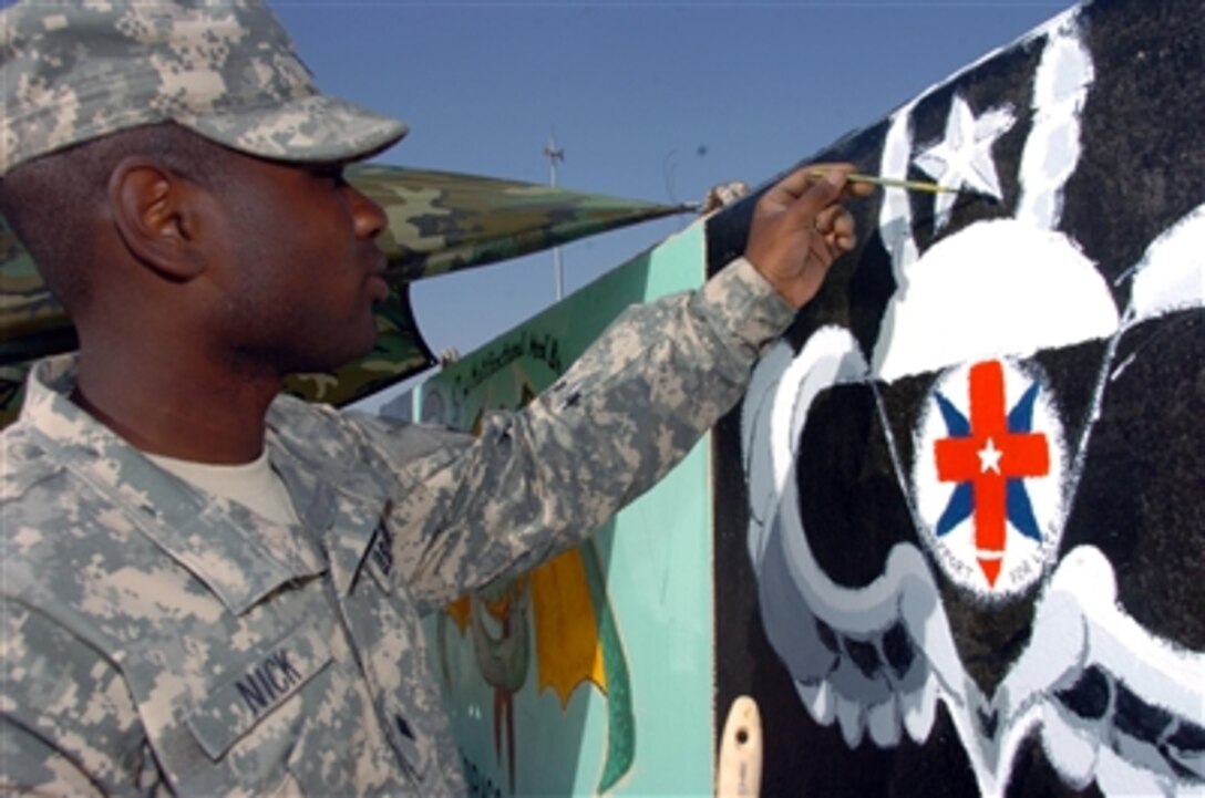 U.S. Army Spc. Quinton Nick paints his unit emblem on a barrier in Kuwait before moving north into Iraq, Sept. 22, 2006. Soldiers use their artistic ability to carry on the tradition of painting barriers before going into Iraq. Soldiers involved were Spc. Ron Montague, who designed the 32nd's sign, and Spc. Michael Vangelderen.