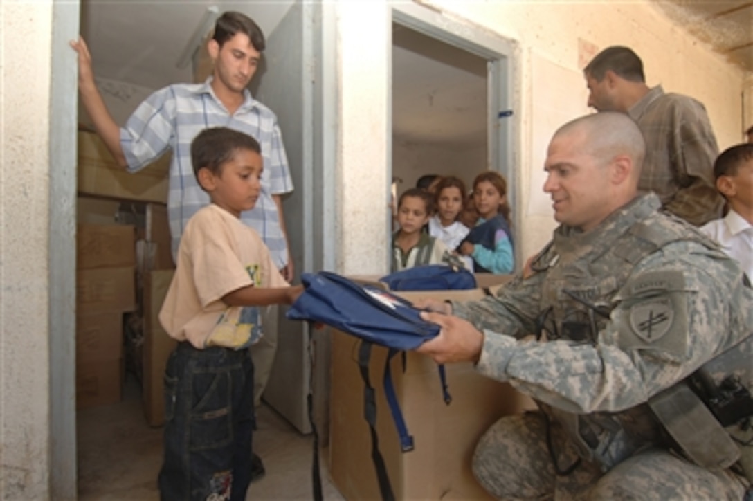 U.S. Army Maj. James Ortoli (right) from the 412th Civil Affairs Unit hands out backpacks to students at the Sayeed Ibraheem School in Seddah, Iraq, on Oct. 3, 2006.  