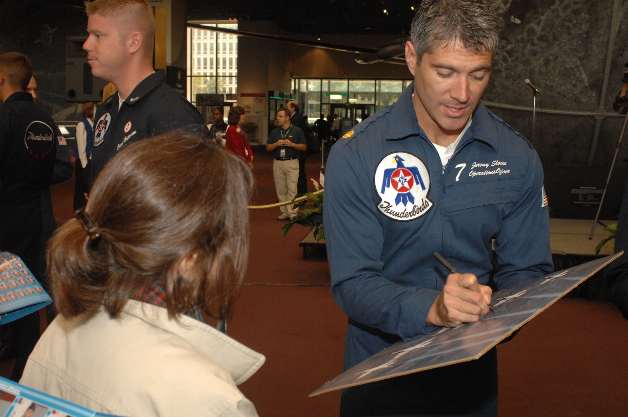 Maj. Jeremy Sloane signs a poster for a fan at the Smithsonian Air and Space Museum Oct. 11 in Washington, D.C. Major Sloane is the Thunderbirds operations officer and was at the Smithsonian as part of a week-long series of events that will culminate with the opening of the Air Force Memorial Oct. 14. (U.S. Air Force photo/Master Sgt. Gary R. Coppage) 
