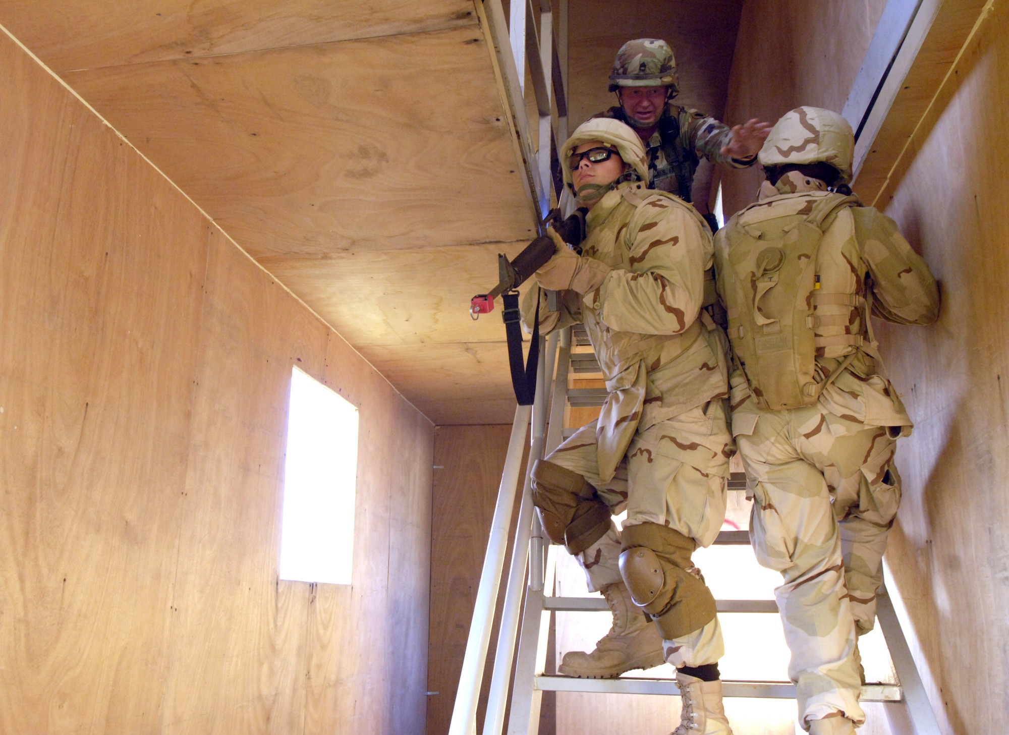 Army Sgt. 1st Class Daniel Criddle (top) instructs 1st Lt. Steven Maddox (left) and Staff Sgt. Travis Haywood on the importance of synchronizing movements when clearing a stairwell Sept. 2 during a course on urban warfare at Camp Shelby, Miss. This drill part of a Urban Assault where Airmen learned how to clear rooms, fire upon a building housing both hostile and peaceful inhabitants and encountering sniper fire. Camp Shelby is one of several Army installations providing training to military personnel preparing to deploy to Southwest Asia.  (U.S. Air Force photo/Master Sgt. Scott Wagers)