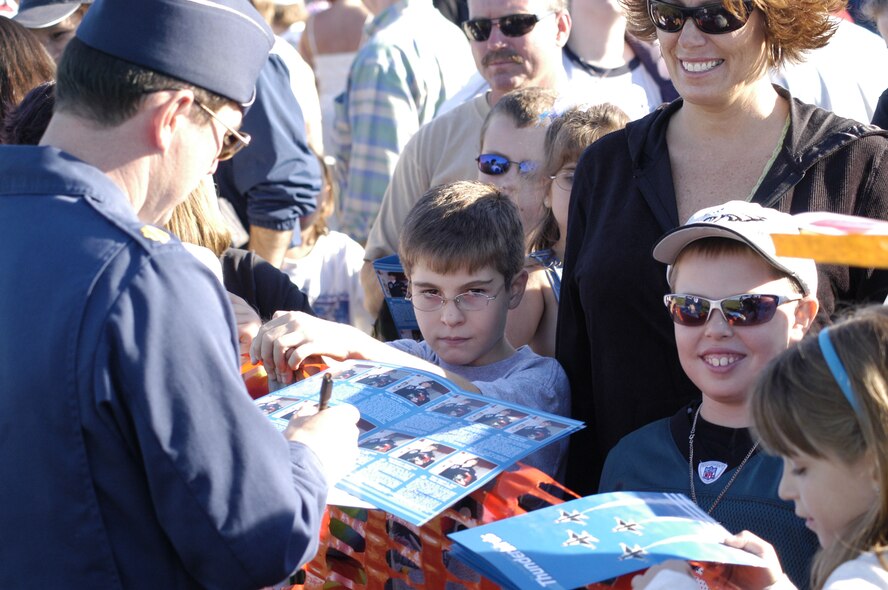 Maj. Dan Mirski, Thunderbird officer flight surgeon, signs a Thunderbirds program for children during the Open House. Several of the Thunderbird officers, including the pilots, signed autographs after the show. (U.S. Air Force photo/Senior Airman James Bolinger)