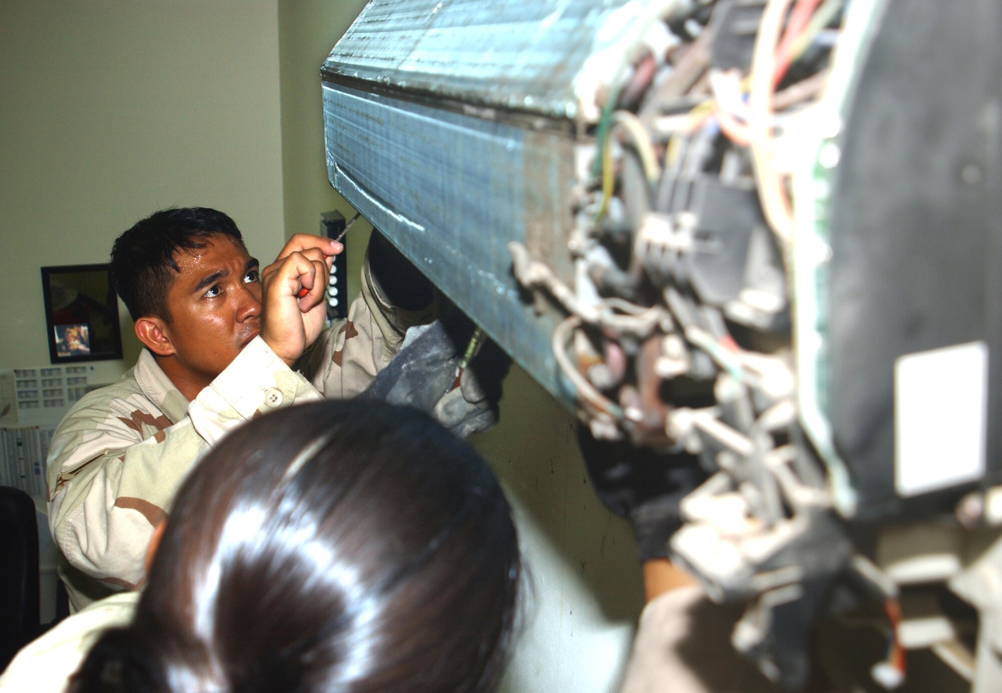 Senior Airman Ernesto Estalilla repairs a wall-mounted air conditioning unit in the third-country national escort office of at this deployed location in Southwest Asia Oct. 11. Airman Estalilla is part of a nine-person team that maintains better than 3,000 air-conditioning units here for about 1,500 people and the 380th Air Expedtionary Wing. He is assigned to the 380th Expeditionary Civil Engineer Squadron and deployed from Yokota Air Base, Japan. (U.S. Air Force photo/Master Sgt. Jason Tudor)