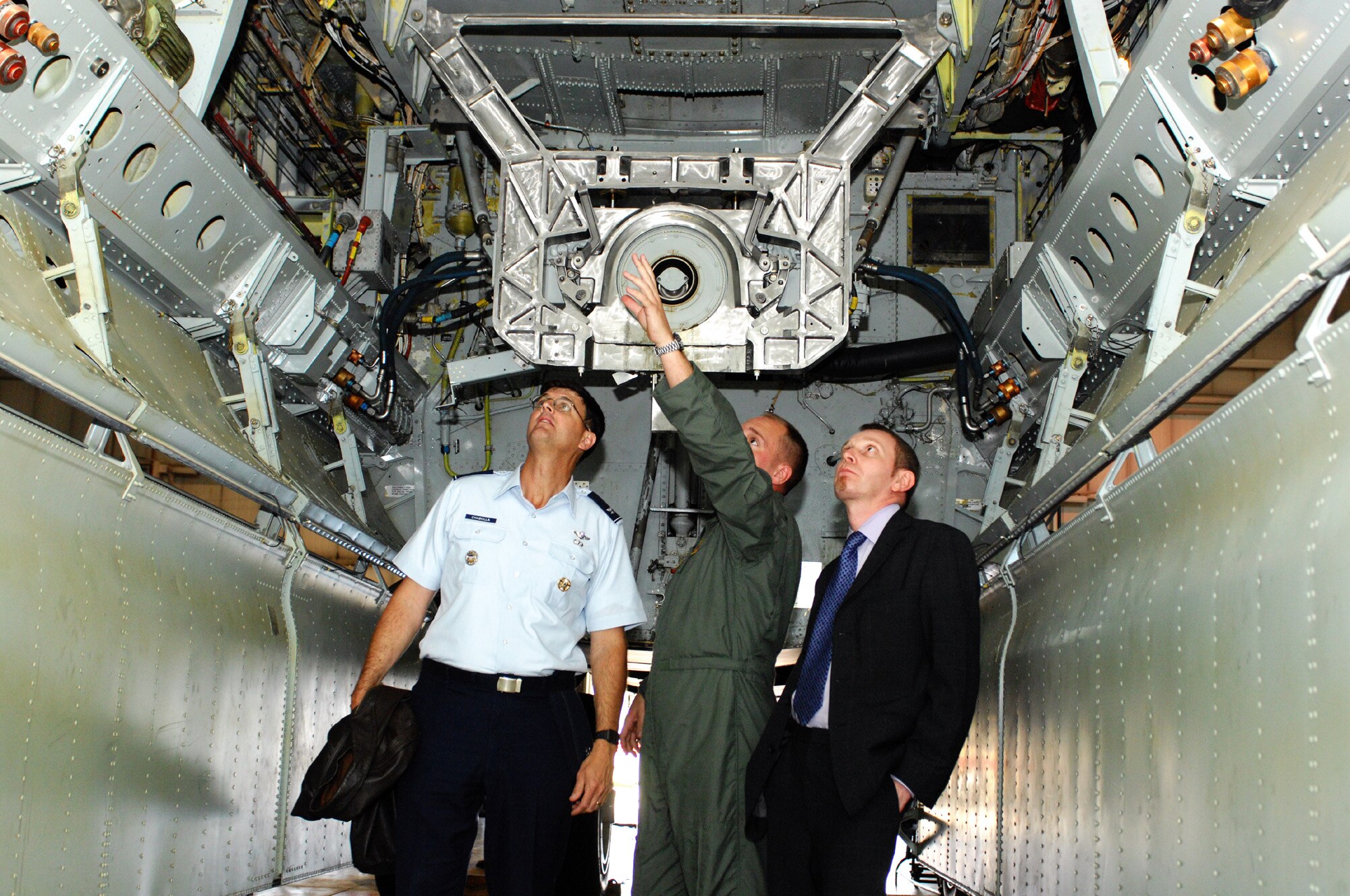 First Lt. Aaron Cook, 23rd Bomb Squadron, (middle), explains the inside of the payload bay of a B-52H Stratofortress, to Col. Steve Chabolla, Office of the Secretary of Defense Policy, and Nigel Basing, British Ministry of Defence, during a delegation visit here Oct. 5.