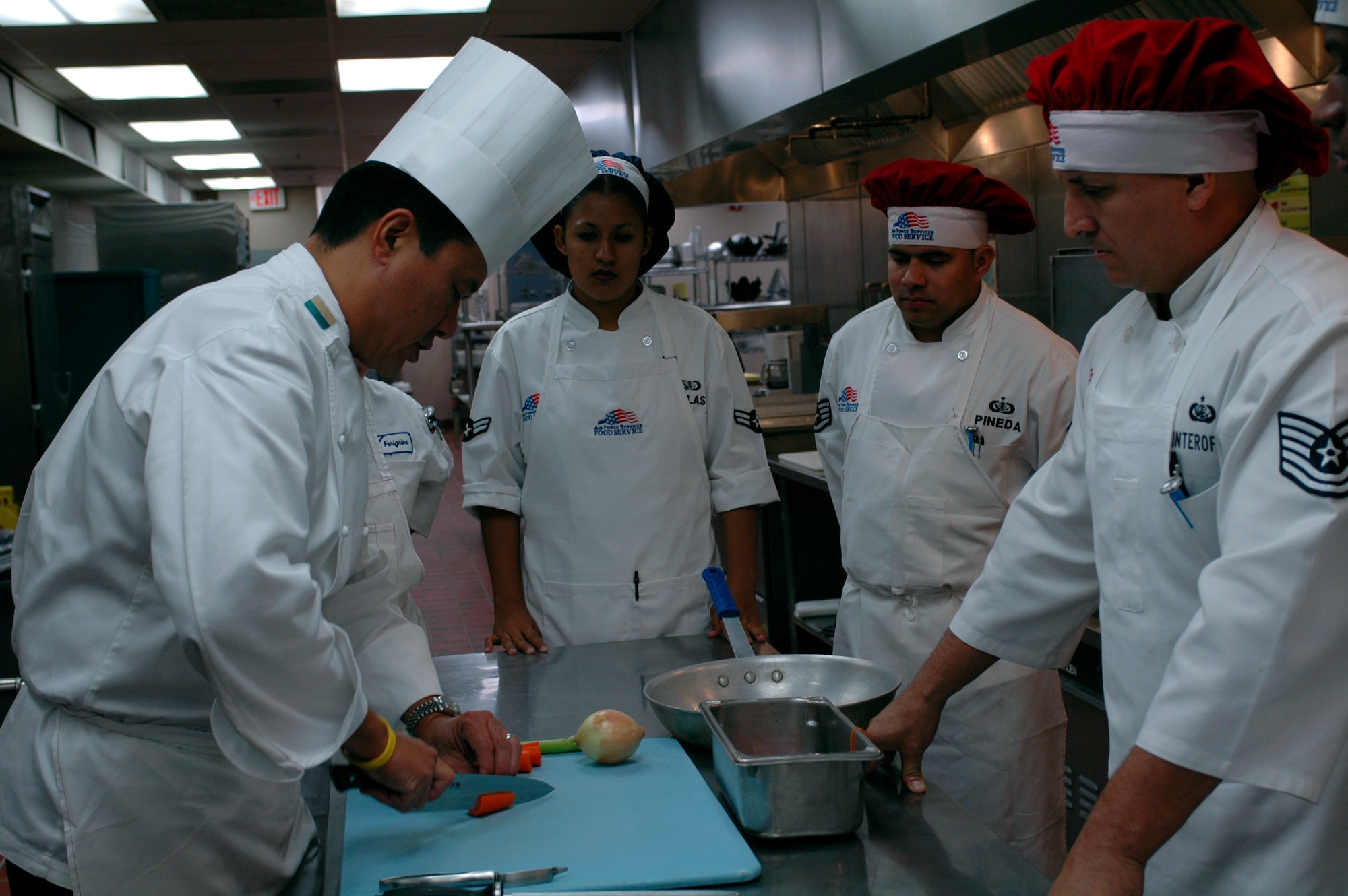 Chef Thomas Wong, (left), Culinary Institute of America instructor, demonstrates advanced cutting techniques to Food Services team members. The Culinary Institute of America holds a one-week, two-phase program designed help Travis cooks enhanced their cooking skills. (U.S. Air Force photo by Staff Sgt. Candy Knight/60th AMW Public Affairs)