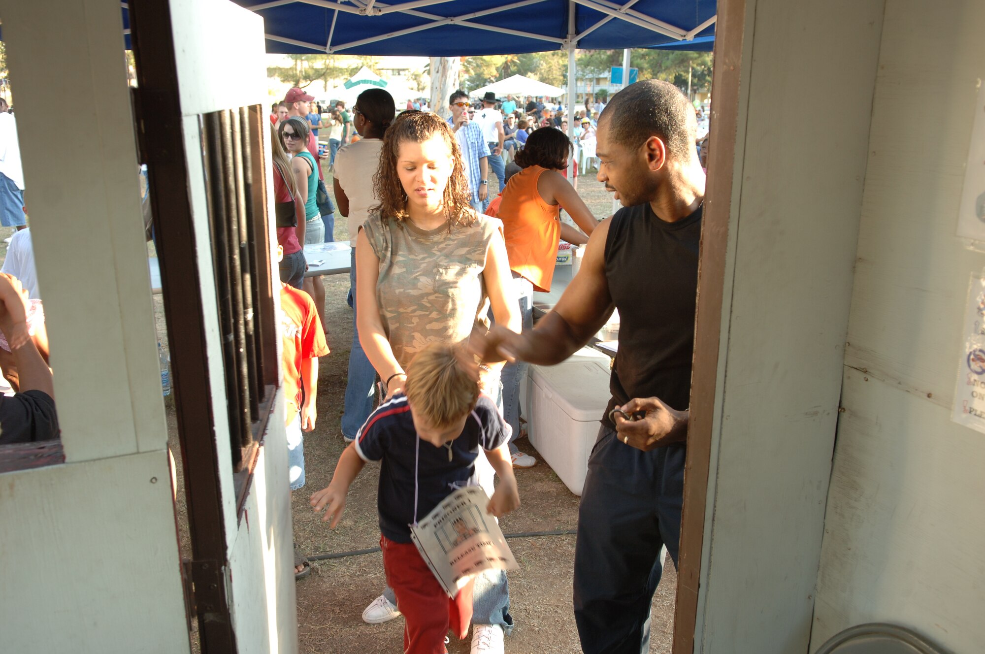 Airman Jennifer Kilthau, 39th Logistics Readiness Squadron customer service apprentice, helps a base youth  into the mock jail while the “warden” looks on. (U.S. Air Force photo by Staff Sgt. Chris Galindo) 