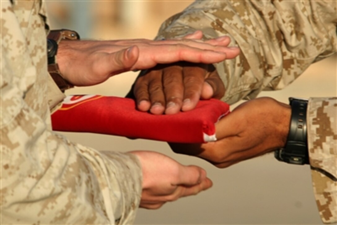 The Marine Corps flag is passed from one Marine's hands to another's during a transfer of authority ceremony at Al Asad, Iraq, Oct. 7, 2006.  The Marines with Marine Heavy Helicopter Squadron 463 turned their mission over to the Marines with HMH-363.