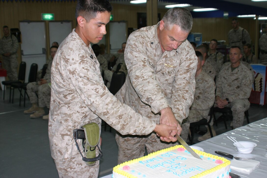 Commander Gary Carr, 51, a Lansing Michigan native and oldest sailor in attendance cuts the cake with help from Hospitalman Ceazar Jaramillo, 20, a Ridgecrest, Calif. native, during the cake cutting portion of the Navy's 231st birthday ceremony aboard Camp Virginia, Kuwait.  The 24th Marine Expeditionary Unit is currently conducting training in and around Camp Virginia during their scheduled six-month deployment.