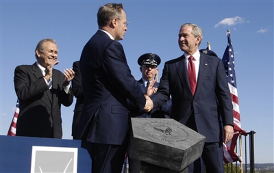 President George W. Bush accepts the Air Force Memorial from Air Force Memorial Foundation Chairman Ross Perot Jr. during a dedication ceremony at its Arlington, Va. location overlooking the Pentagon, Oct. 14, 2006. Secretary of Defense Donald H. Rumsfeld and Air Force Chief of Staff Gen. T. Michael Moseley are shown applauding in the background.
