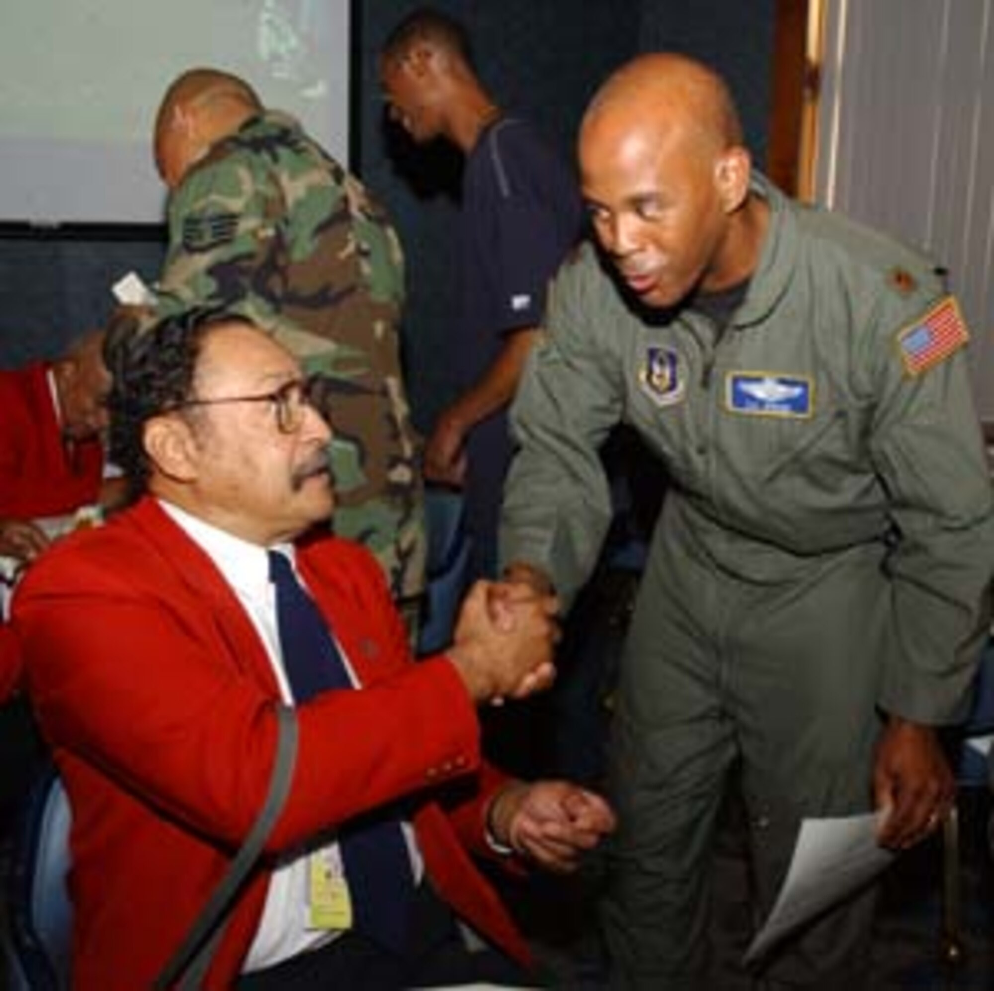 ANDREWS AFB, Md. -- Maj. Eric Jenkins, a pilot with the 459th Air Refueling Wing, shakes hands with Tuskegee Airman, retired colonel, William Broadwater.  Colonel Broadwater and the other famed and historic members of the African-American fighter squadron that escorted U.S. bomber aircraft into enemy territory in World War II, stopped by the Air Force Reserve unit to present an award to wing commander, Col. Stayce D. Harris and the wing during its commander's call.  The award is a thanks to Colonel Harris for her long-ime involvement in Tuskegee Airmen International.  
     Upon the announcement of their presence, the wing members gave a long, rousing, standing ovation.  The Tuskegee Airmen finished off their day at the Club at Andrews.  There, they signed photos of their famous "Redtail" fighter aircraft refueling a B-24, a piece of art created by artist Mickey Harris.