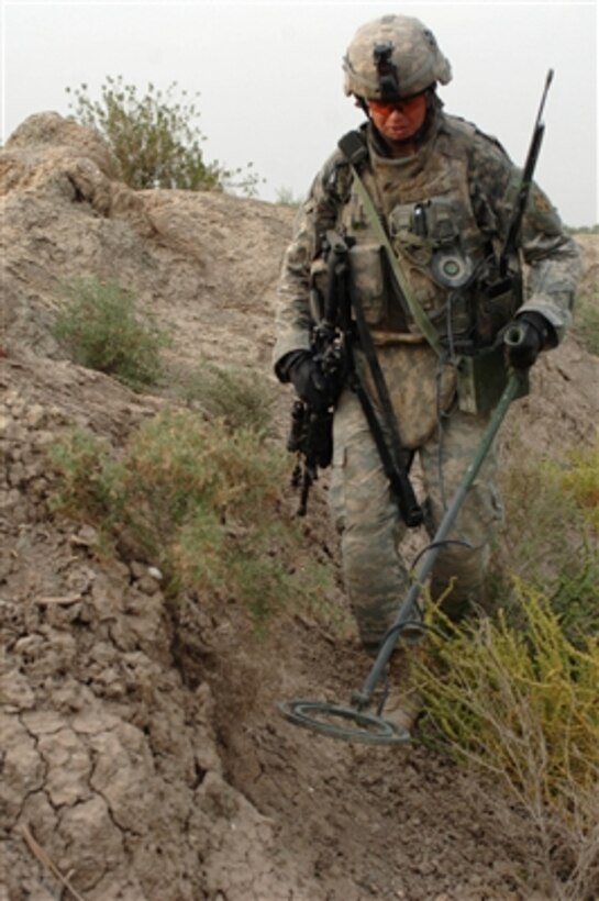 A U.S. Army soldier uses a metal detector to locate possible buried weapons near a farmhouse in a village outside Baghdad, Iraq, on Oct. 12, 2006. This soldier is attached to Alpha Company, 1st Battalion, 22nd Infantry Battalion, 1st Brigade Combat Team, 4th Infantry Division.  