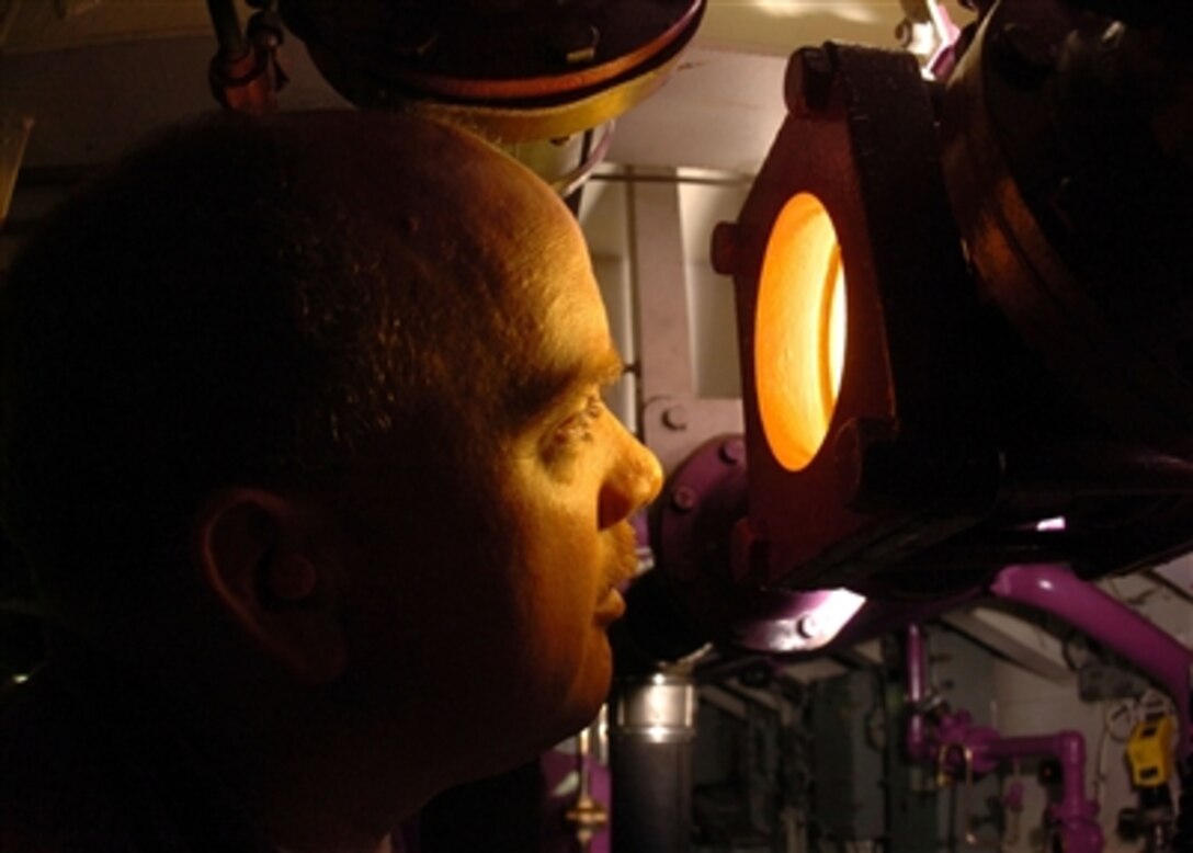 Navy Petty 3rd Class Kevin Luby looks through an illuminated sight glass to check for impurities in aviation fuel inside the JP-5 pump room aboard the aircraft carrier USS John C. Stennis (CVN 74) on Oct. 11, 2006.  Luby is a Navy aviation boatswainís mate who specializes in aircraft fuel.  