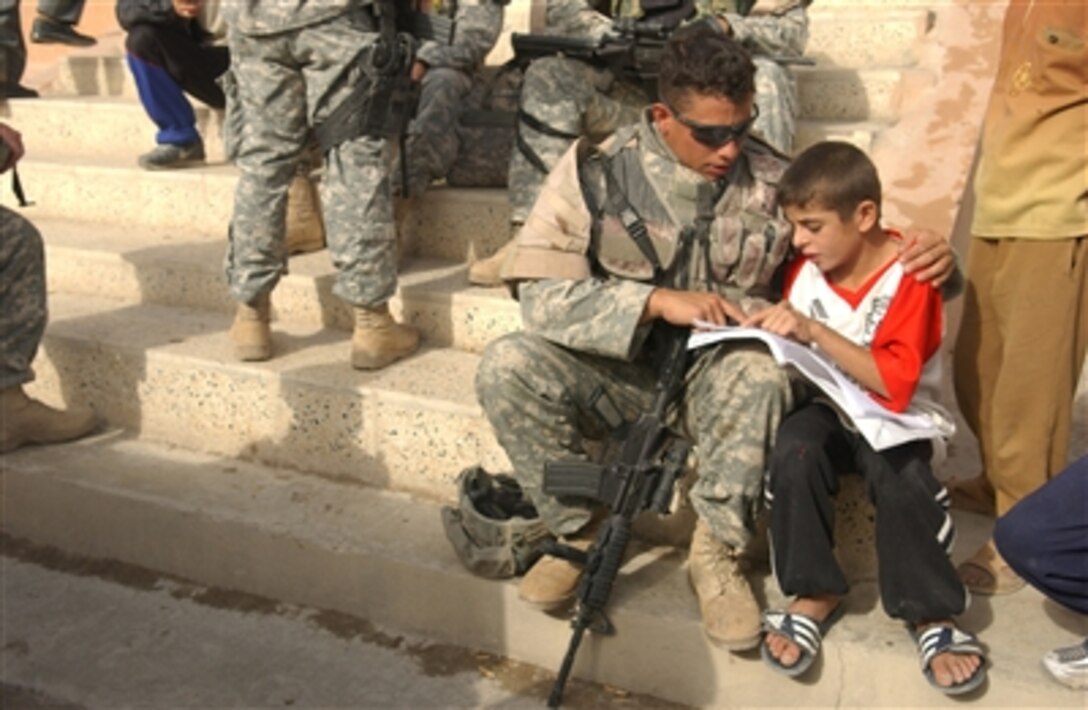 Spc. Eric Adolph uses the steps as an impromptu classroom as he helps an Iraqi boy with his English lesson in Tall Afar, Iraq, on Oct. 15, 2006.  Adolph is attached to the U.S. Armyís Bravo Company, 352nd Civil Affairs Battalion.  