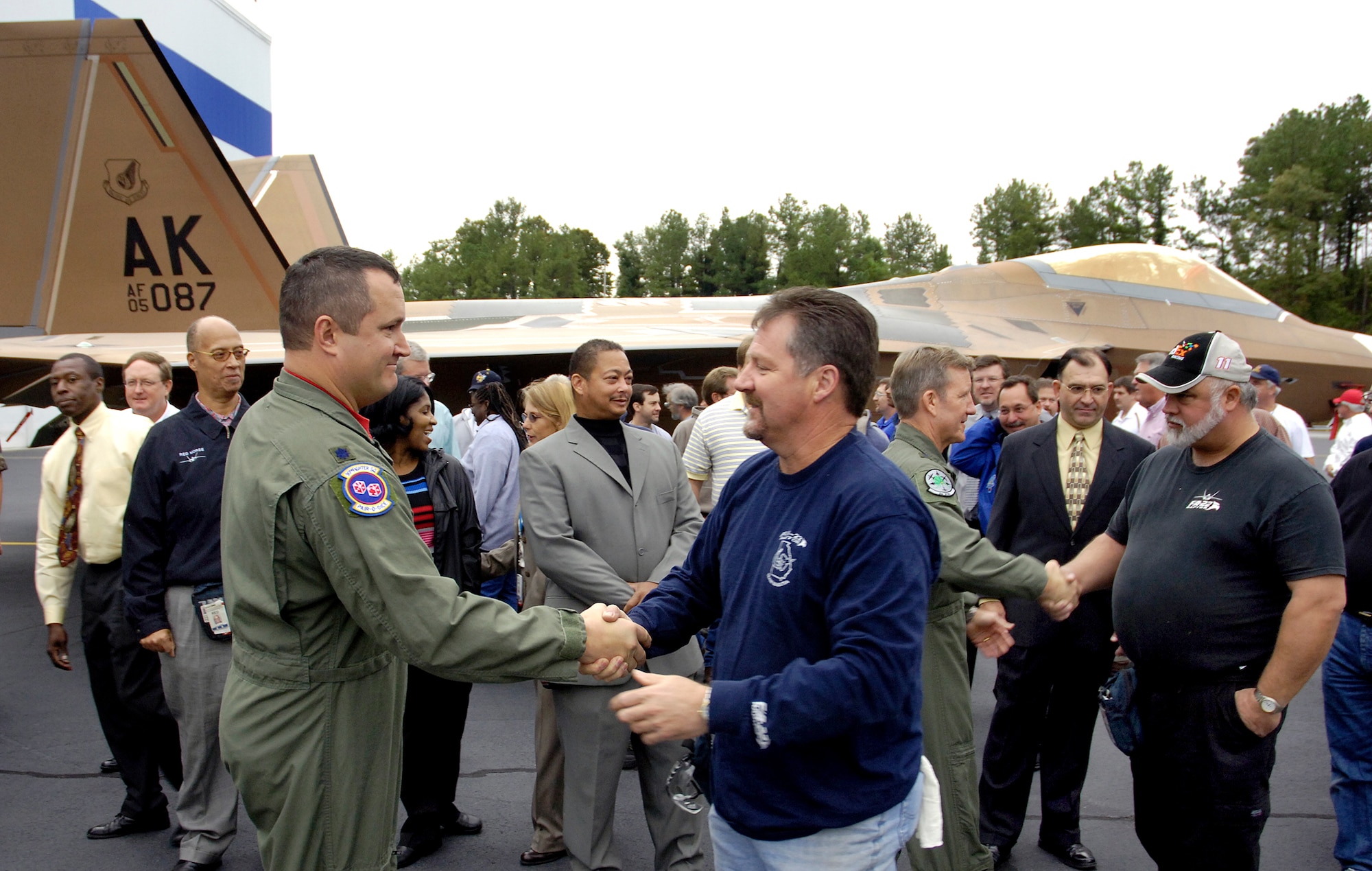 Lt. Col. Michael Shower (front) and Brig. Gen. Herbert Carlisle shake hands with Lockheed Martin employees after the roll-out of the Pacific Theater's first combat ready F-22 Raptor, destined for the 3rd Wing at Elmendorf Air Force Base, Alaska.  General Carlisle is the 3rd Wing commander, and Colonel Shower is the 90th Fighter Squadron's Detachment 1 commander. (Photo by John Rossino)