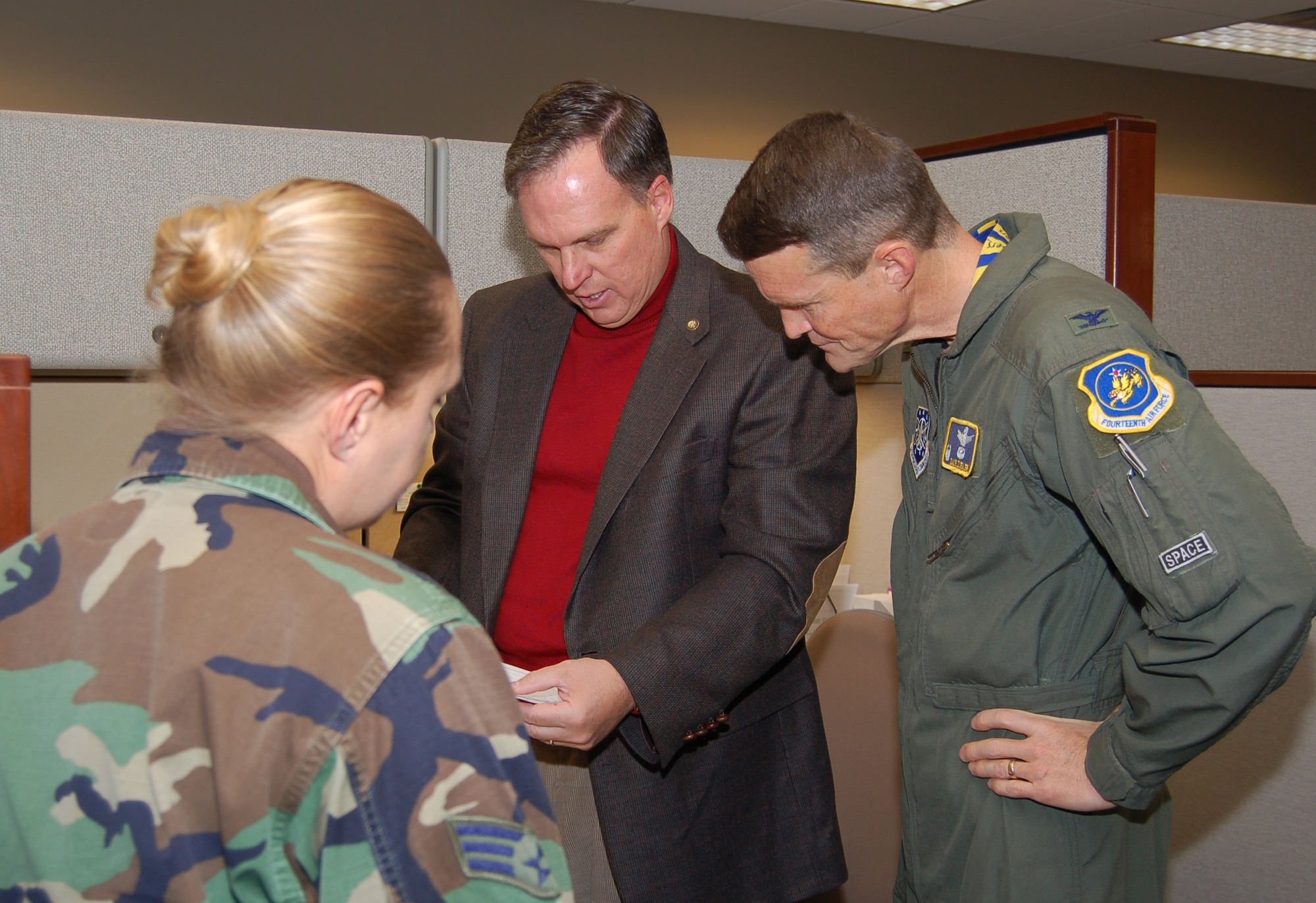 Senior Airman Amy Daub, from the 460th Medical Group, watches and listens as Scott Rogers, from the 460th Contracting Squadron, briefs 460th Space Wing Commander Col. David Ziegler about his ongoing projects. Airman Daub participated in the shadow program, in which a junior enlisted member tags along with Colonel Ziegler for two days, Oct. 17 and 18.