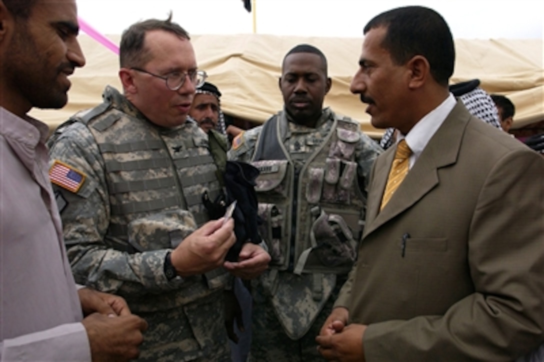 U.S. Army Col. Gary Johnston, the commander of Gulf Region South, U.S. Army Corps of Engineers, gives the school headmaster a coin following the ribbon cutting ceremony for the Salah Hadi Obid Elementary School in Afak, Iraq, Oct. 11, 2006.