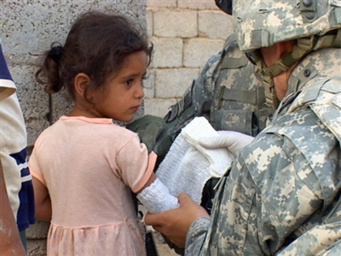 U.S. Army Sgt. 1st Class Matthew K. Harris bandages the burns on an Iraqi girlís right arm during a presence patrol in Rushdi Mullah, Iraq, on Oct. 10, 2006. Harris is with 2nd Platoon, Bravo Company, 4th Battalion, 31St Infantry Regiment, 10th Mountain Division. 